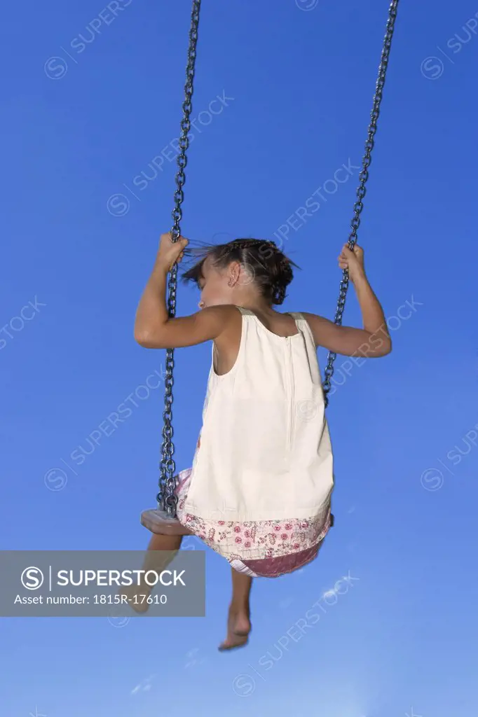 Girl (7-9) sitting on swing, rear view