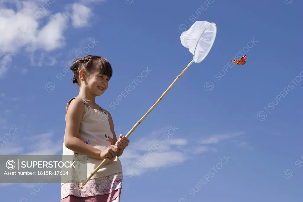 Girl (7-9) holding net, trying to catch butterfly