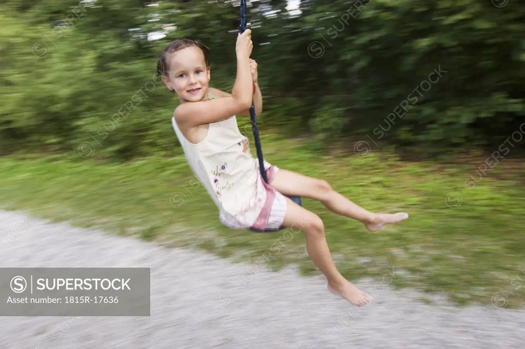 Girl (7-9) sitting on swing, blurred motion