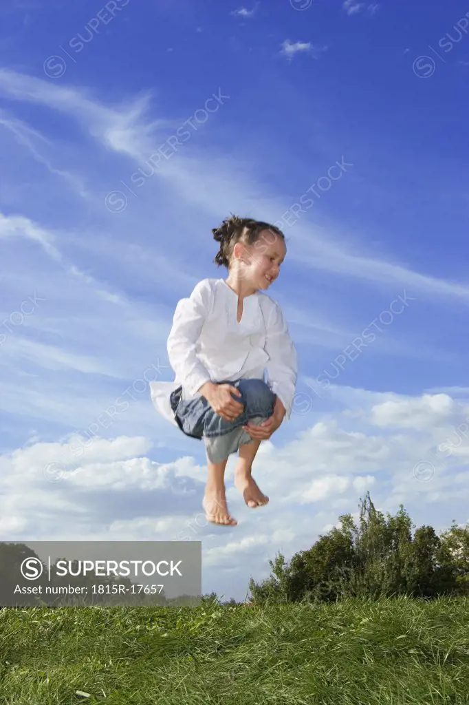 Girl (7-9) jumping in meadow