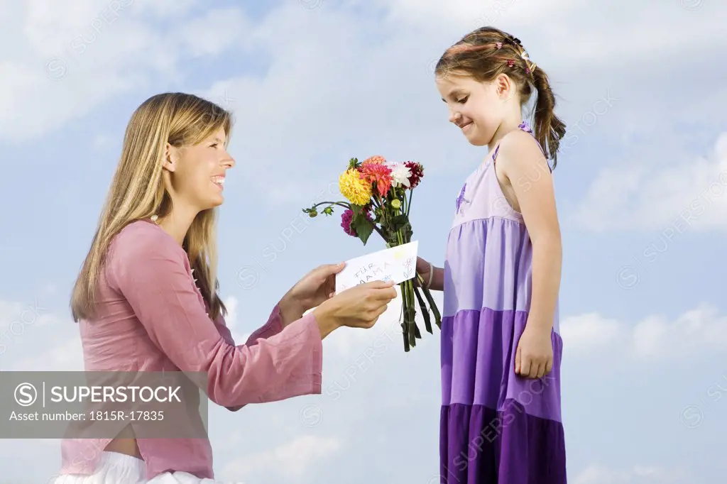 Mother and daughter, girl holding bunch of flowers