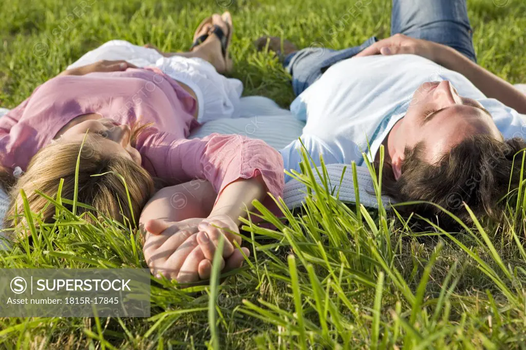 Couple lying in meadow, hand in hand
