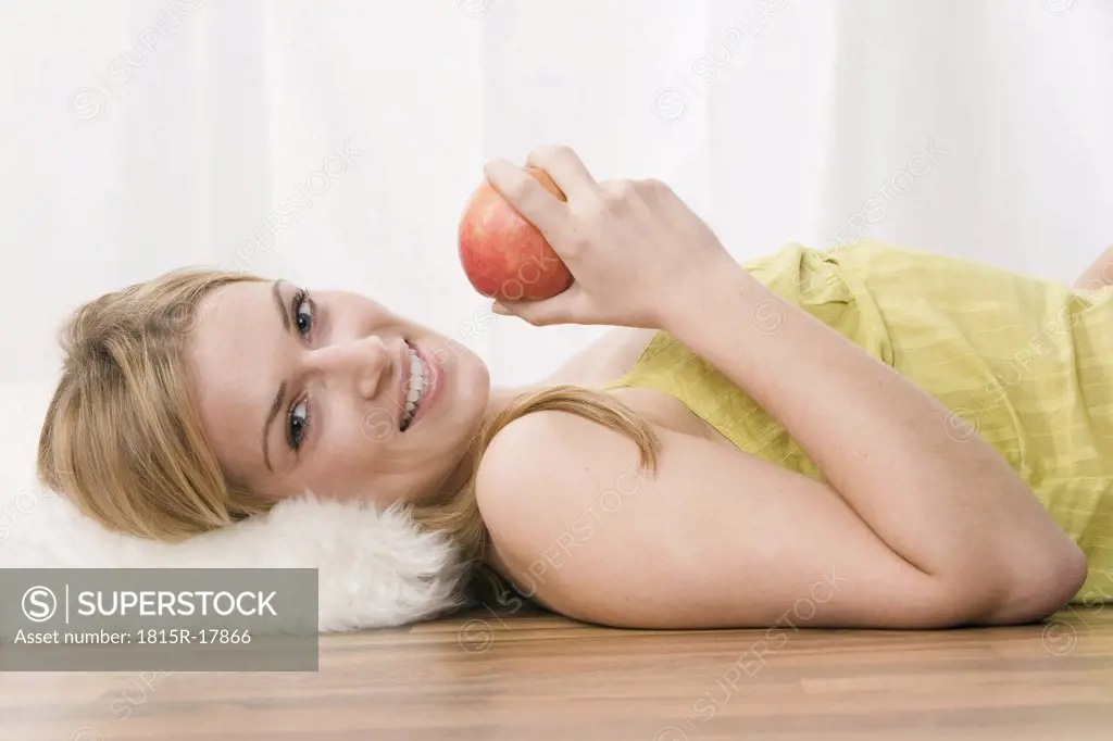 Blonde woman holding an apple, portrait