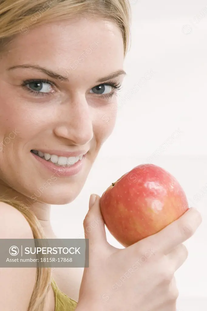 Blonde woman holding an apple, portrait
