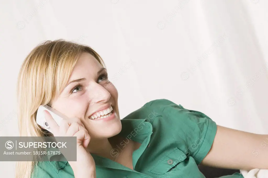 Blonde woman using mobile phone, smiling, portrait
