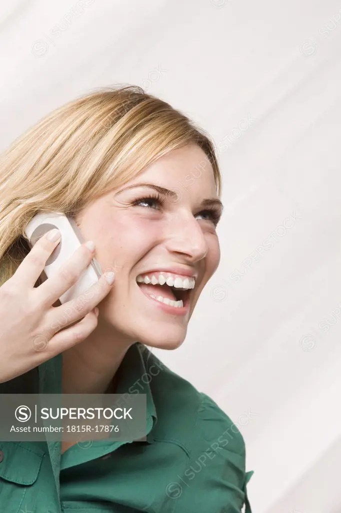 Blonde woman using mobile phone, laughing, portrait