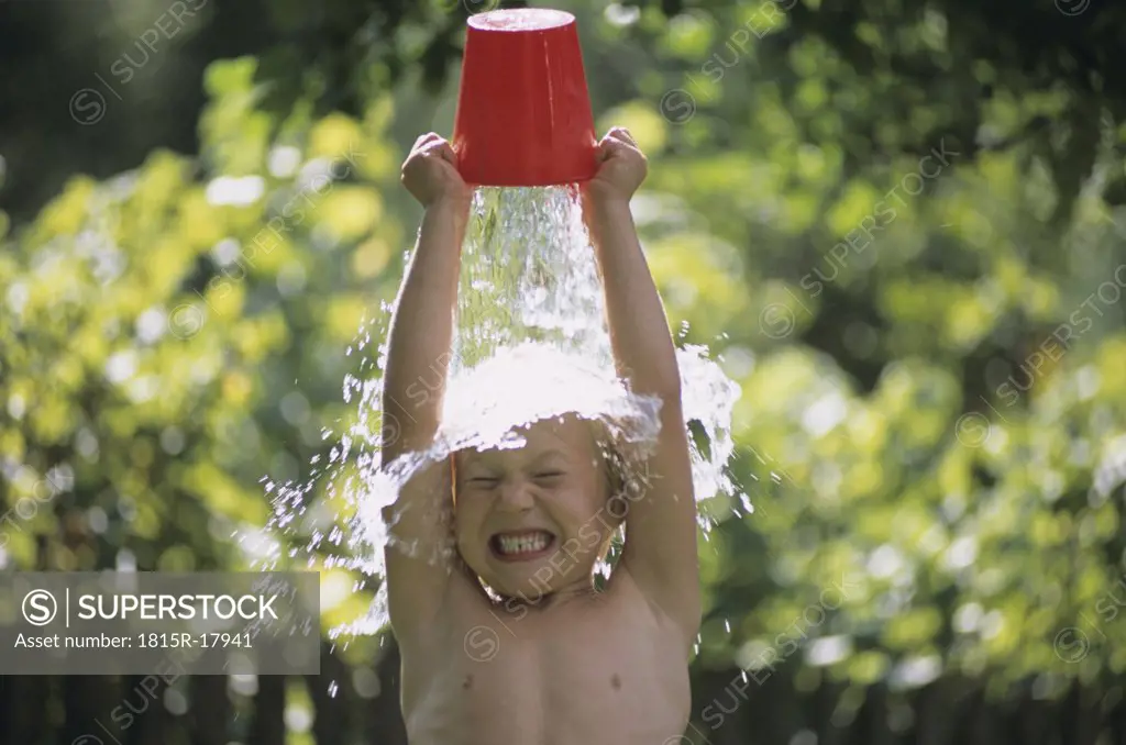 Boy pouring water over head, outdoors