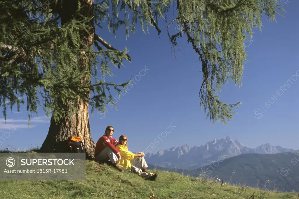 Couple having a break under a tree in the mountains