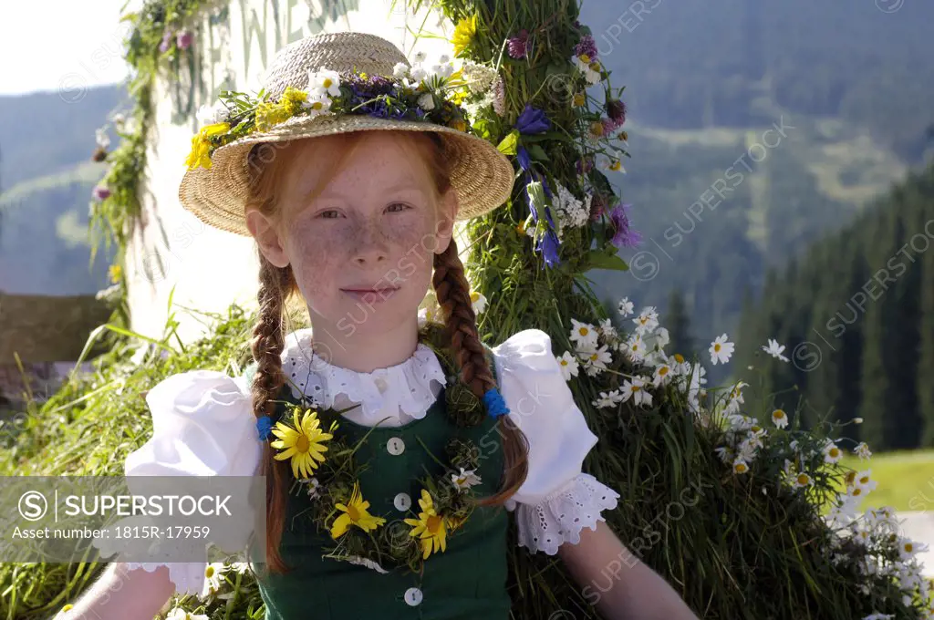 Girl in traditional costume sitting on a waggon, Salzburger Land, Austria