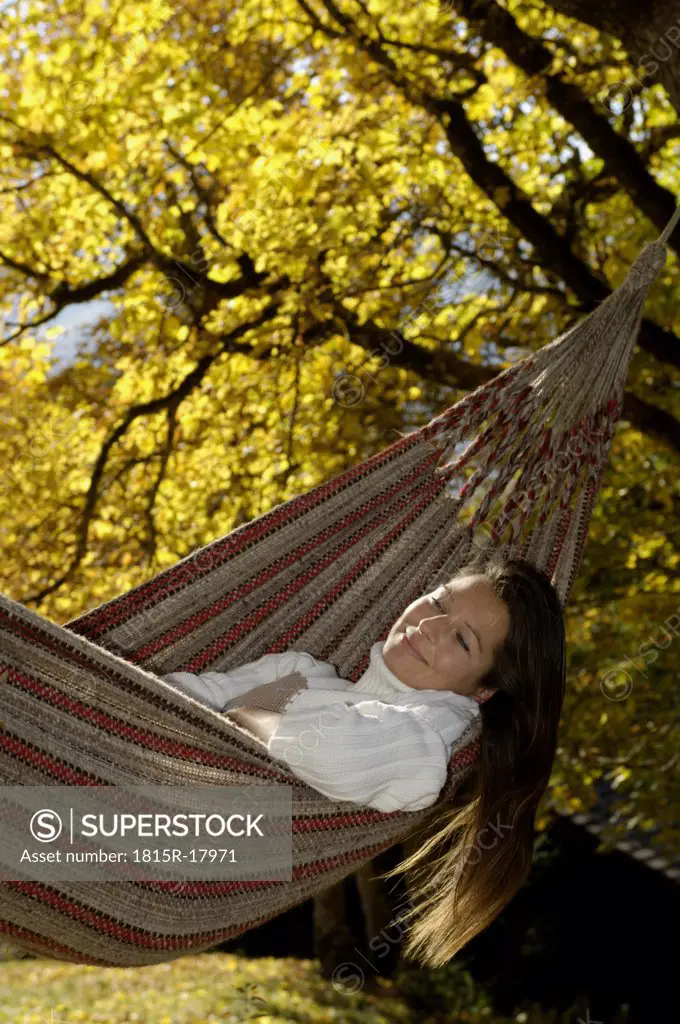 Young woman lying in hammock, smiling