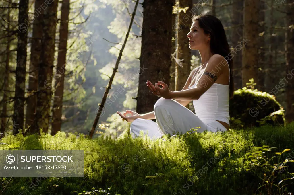 Woman meditating in forest, low angle view