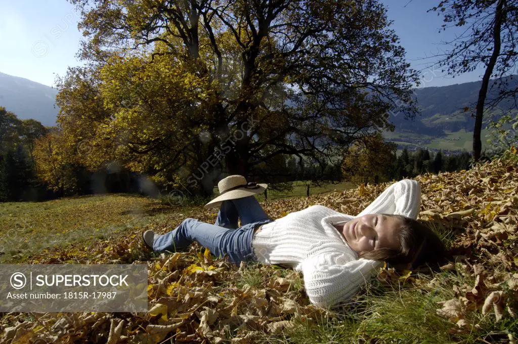 Young woman lying on autumn leaves, portrait