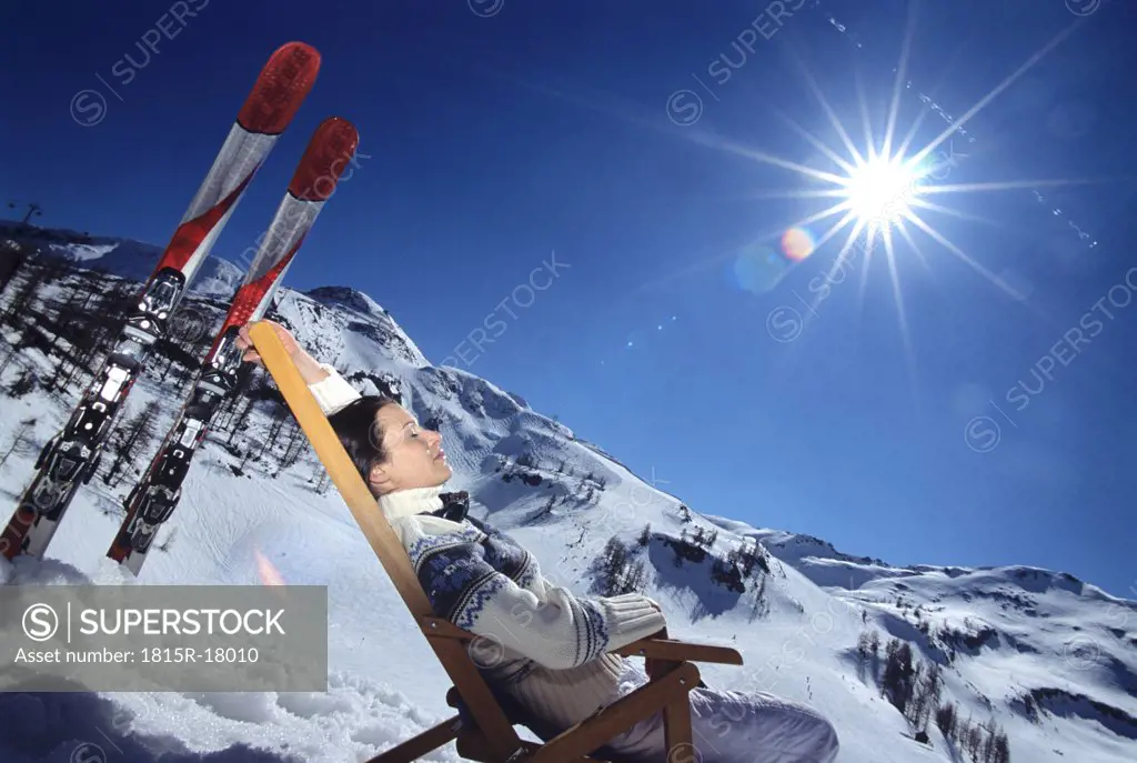 Woman relaxing on deckchair in alps, side view