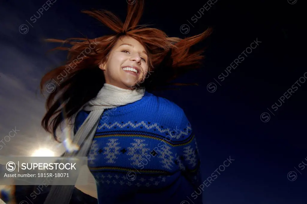 Young woman in jumper smiling, outdoors