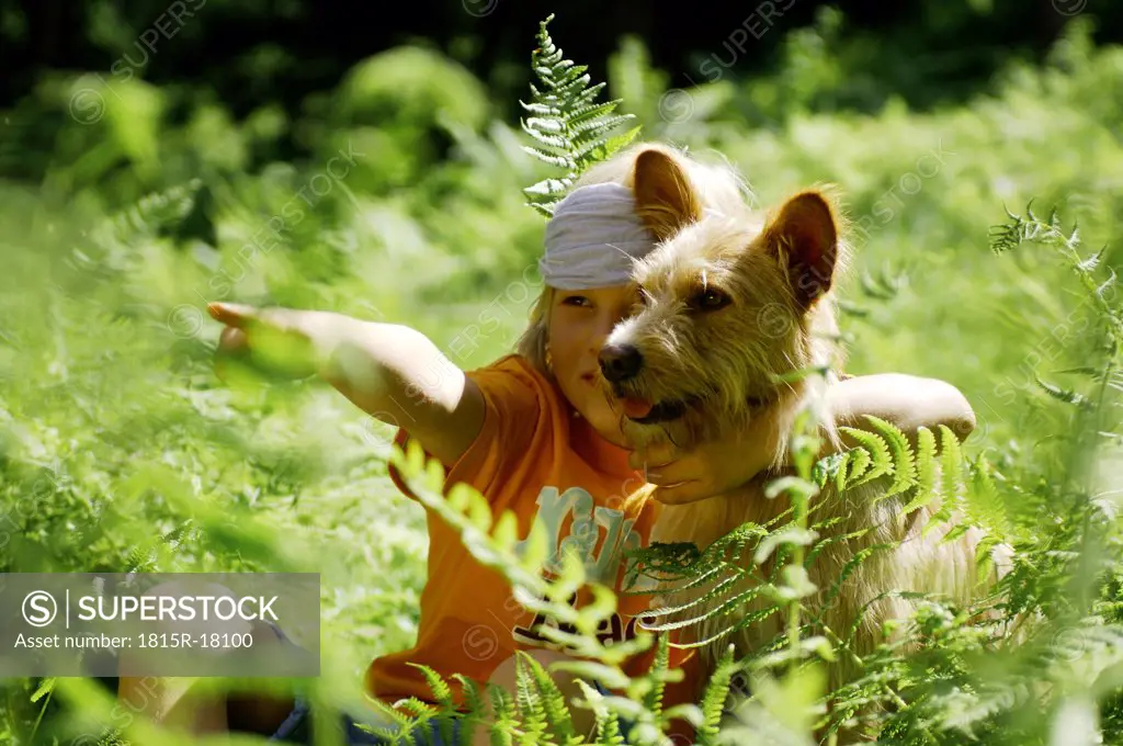 Boy (8-11) sitting with dog, pointing