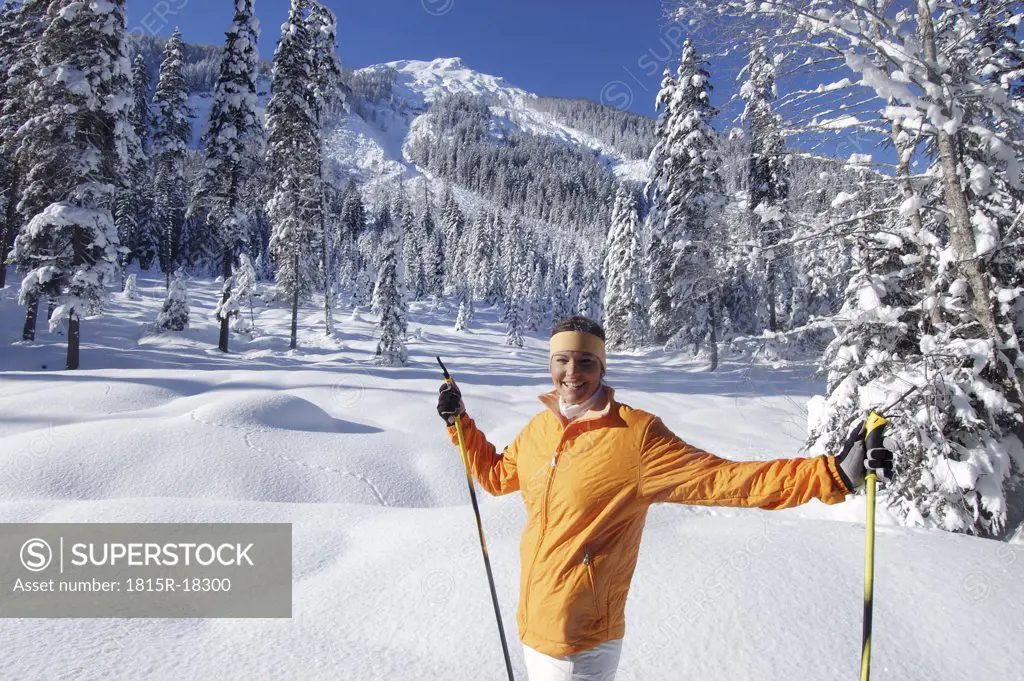 Young woman in snow, holding ski pole, smiling, elevated view