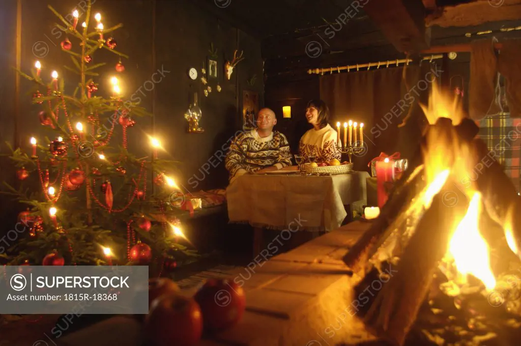 Mid adult couple in alpine hut, looking at Christmas tree