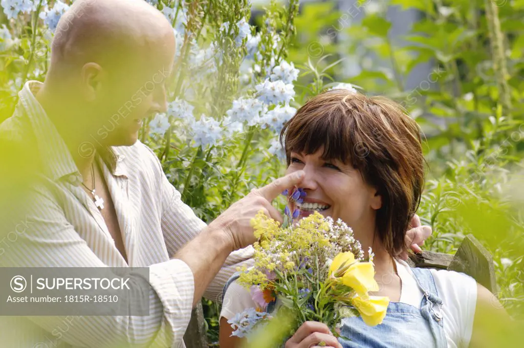 Couple in garden, woman holding bunch of flowers
