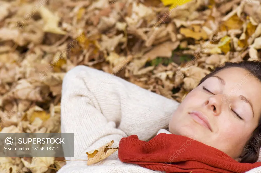 Woman lying on autumn leaves, portrait, close-up