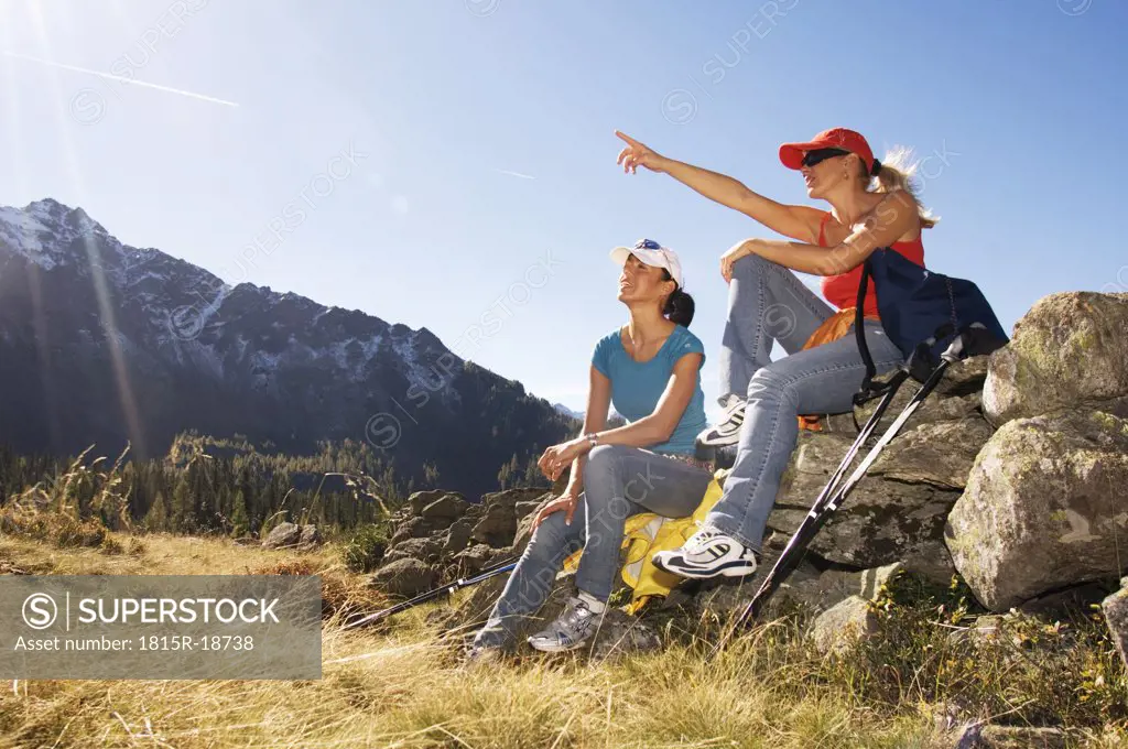 Two women in mountains, sitting on rock