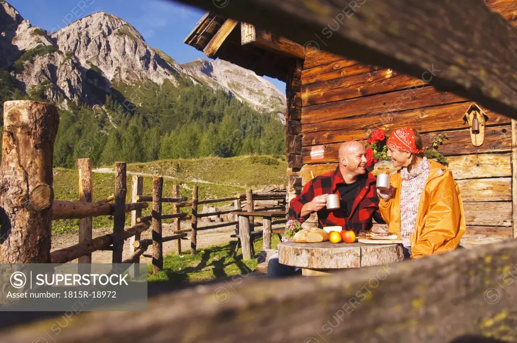 Couple sitting in front of alpine hut