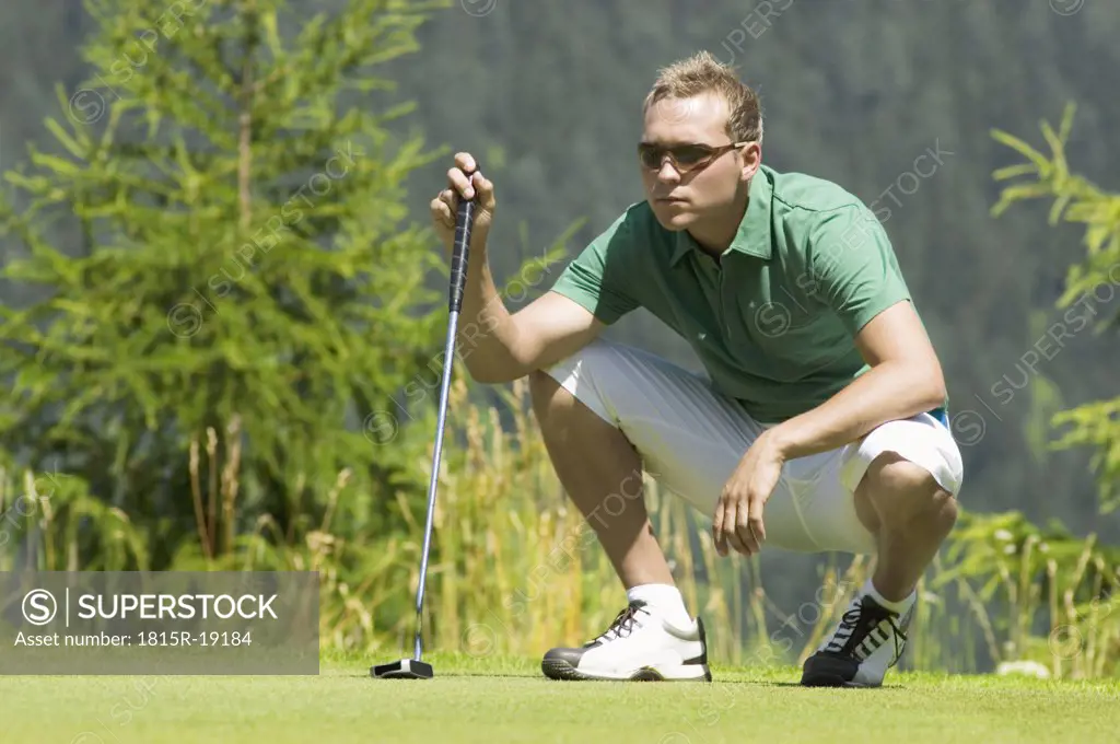 Golf player squatting on golf course