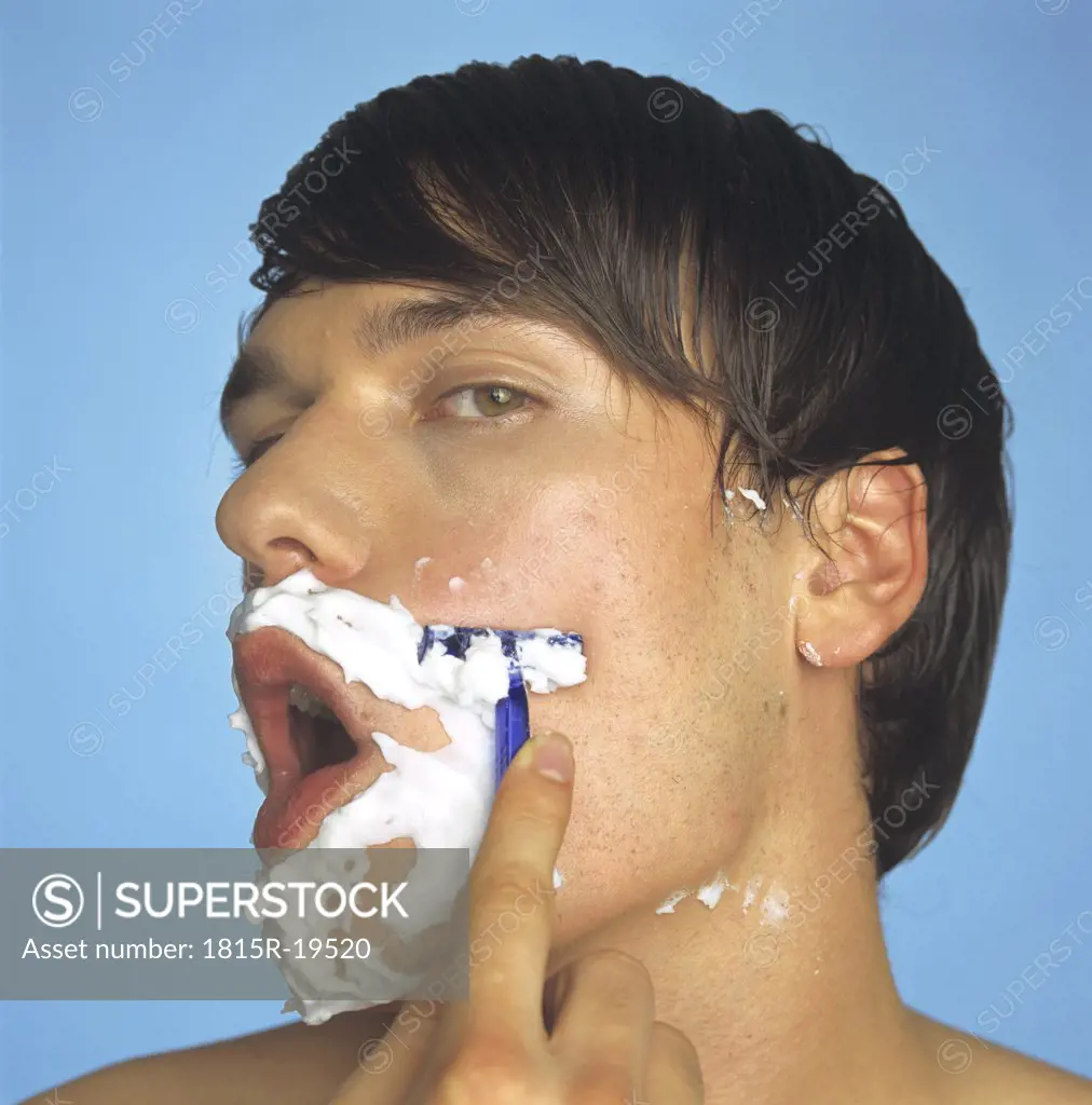 Young man shaving, portrait, close-up
