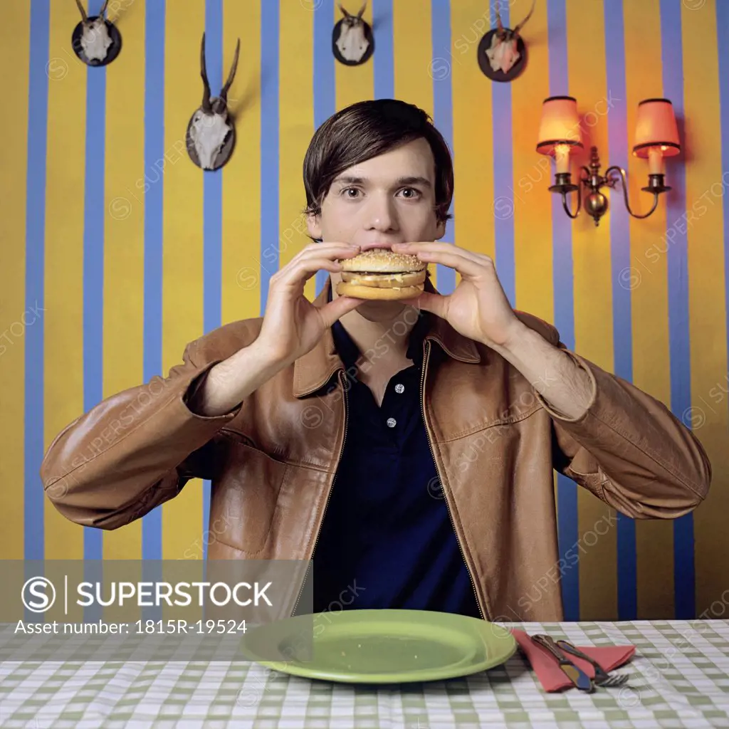 Young man eating burger, portrait
