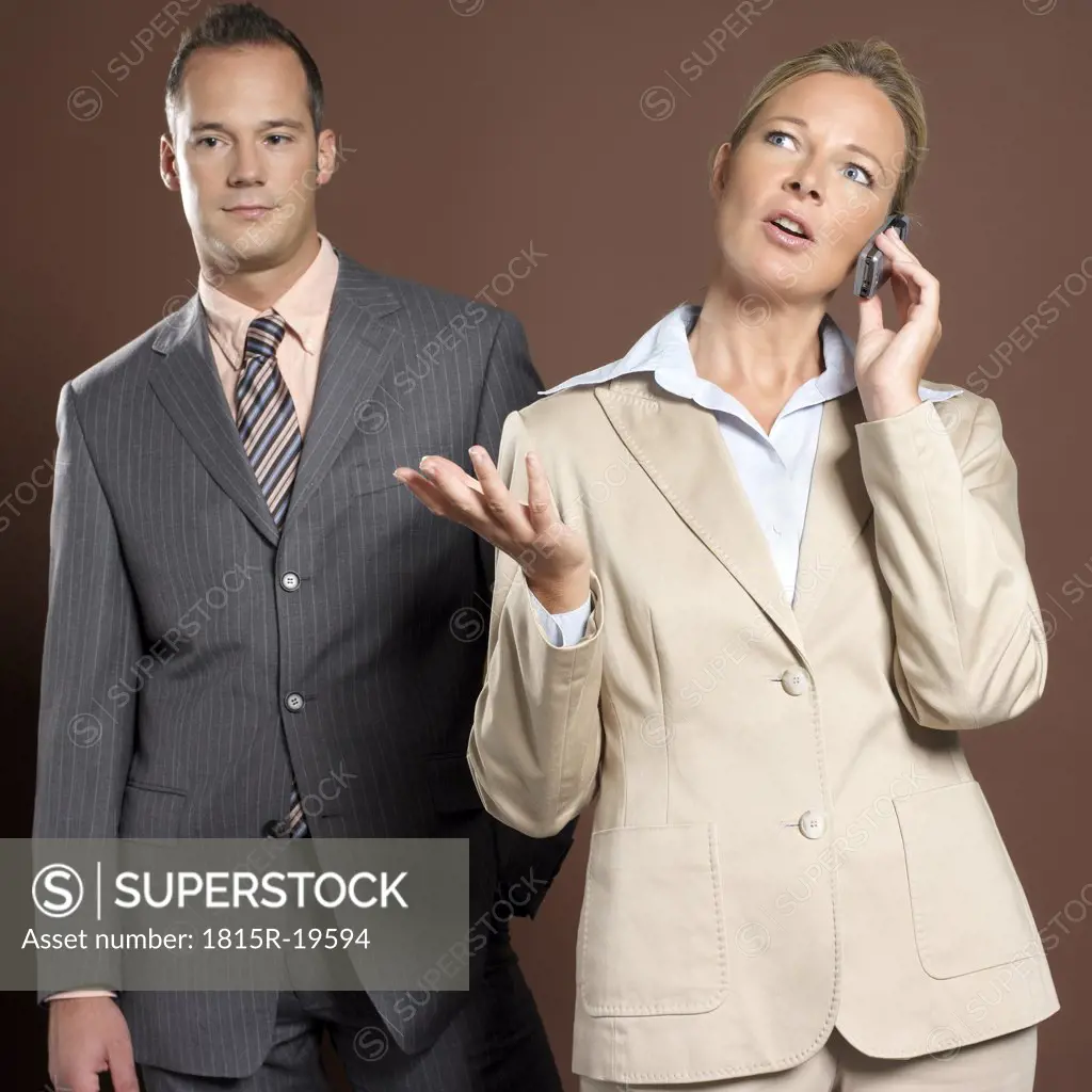 Businessman and businesswoman, woman holding mobile phone