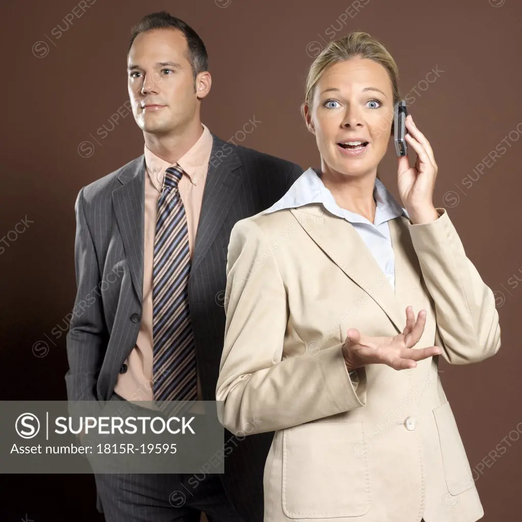 Businessman and businesswoman, woman holding mobile phone