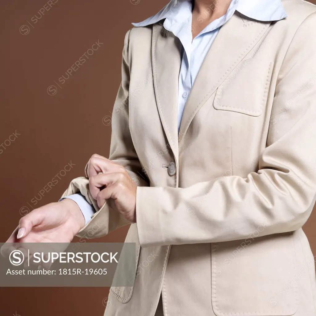 Businesswoman, close-up, rolling up sleeves