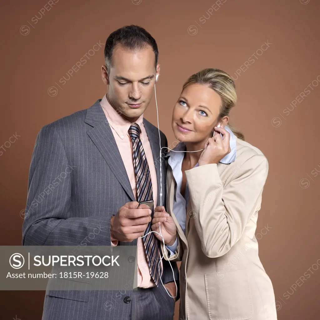 Businessman and businesswoman listening to mp3 player