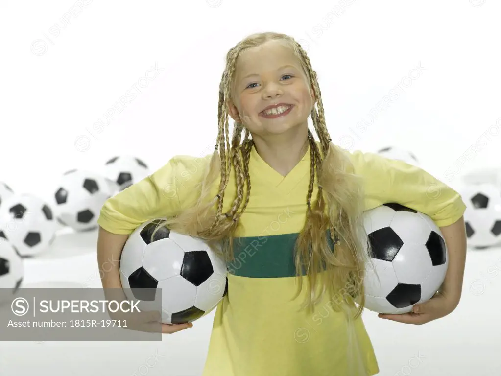 Girl (8-11) holding soccer ball under arms