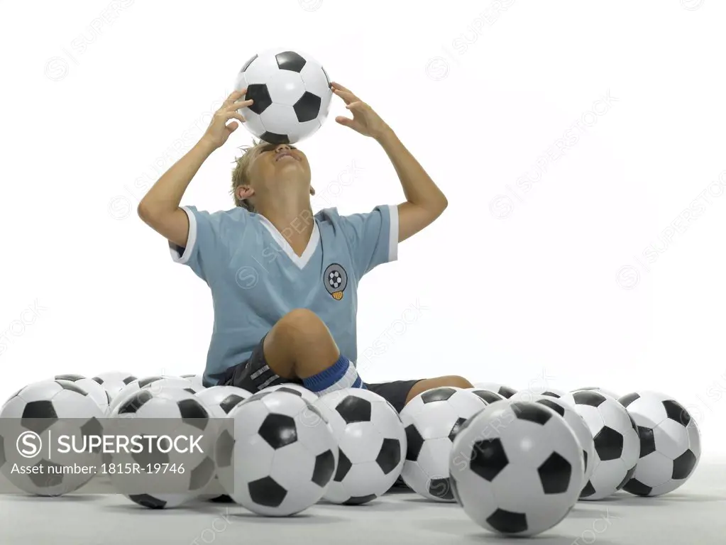 Boy (10-13) balancing football on forehead