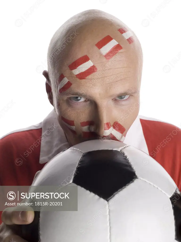 Man with Austrian flag painted on face, kissing football, portrait, close-up