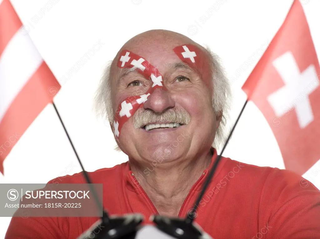 Old man with Swiss flag painted on face holding football, Austrian and Swiss flag aside