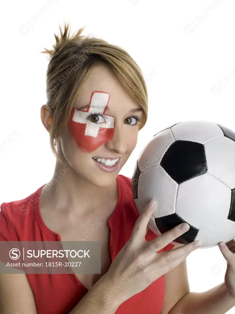 Woman with Swiss flag painted on face, holding football, portrait