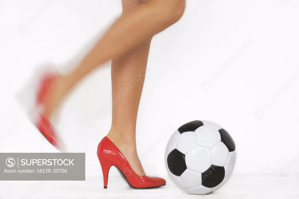 Woman with red high heels kicking a soccer ball, detail