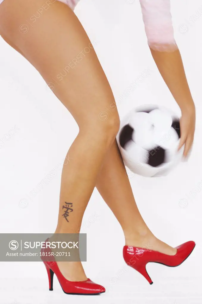 Woman with red high heels holding soccer ball