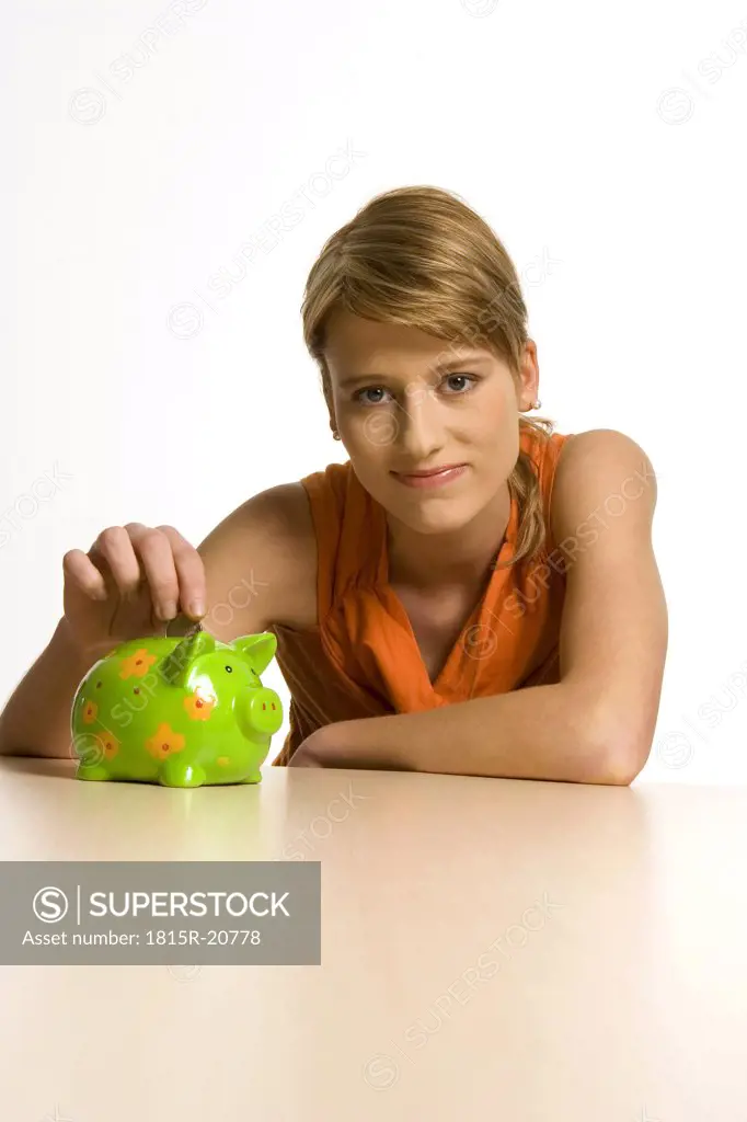 Young woman with green piggy bank, portrait