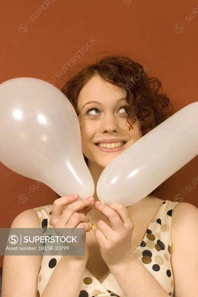 Young woman holding balloon, looking up, close-up