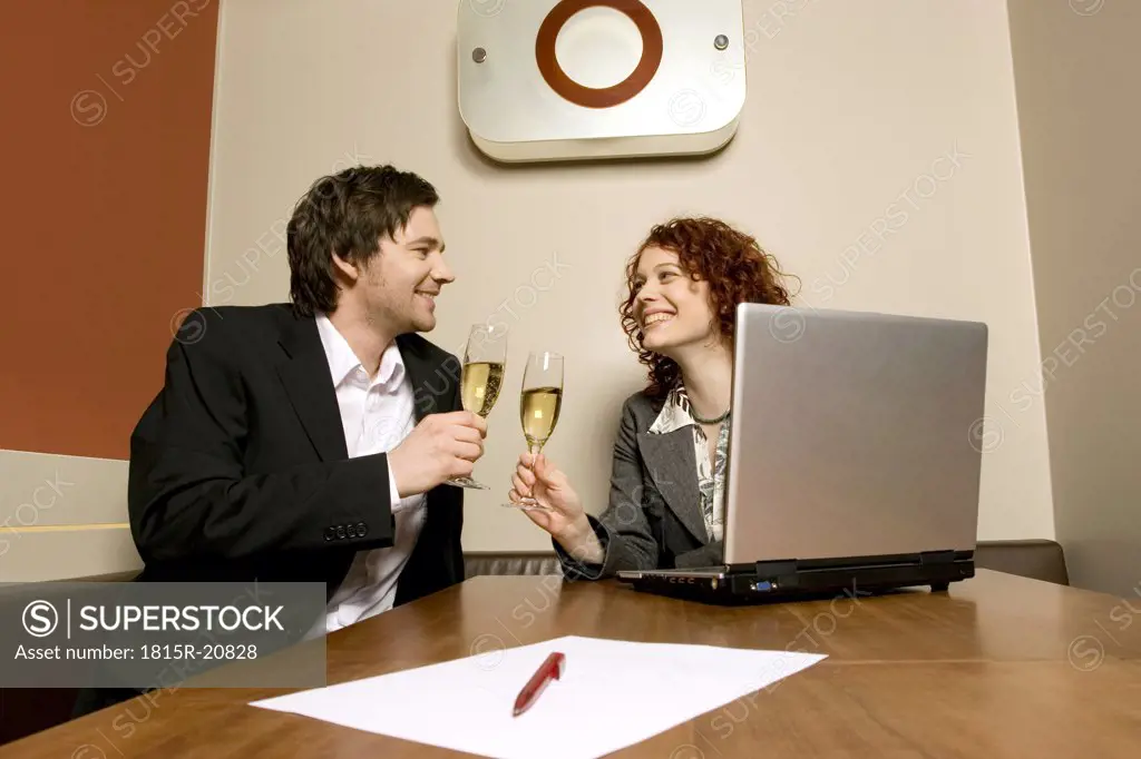 Man and woman with laptop, drinking champagne