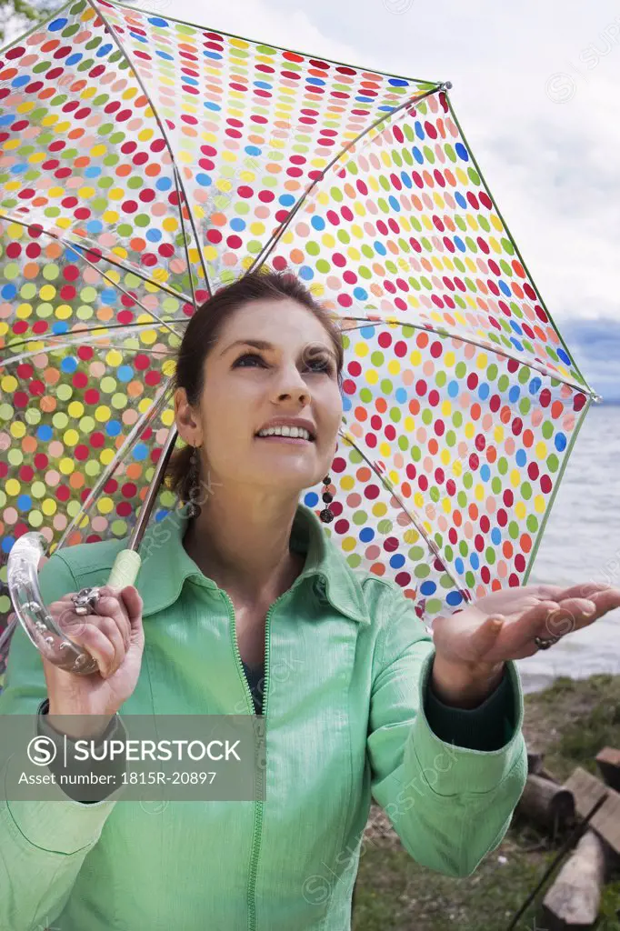 Young woman holding umbrella, looking up, close-up