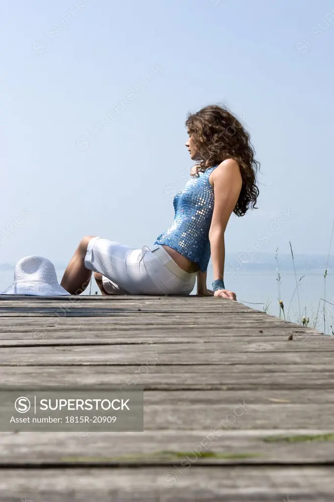 Young woman sitting on jetty, side view