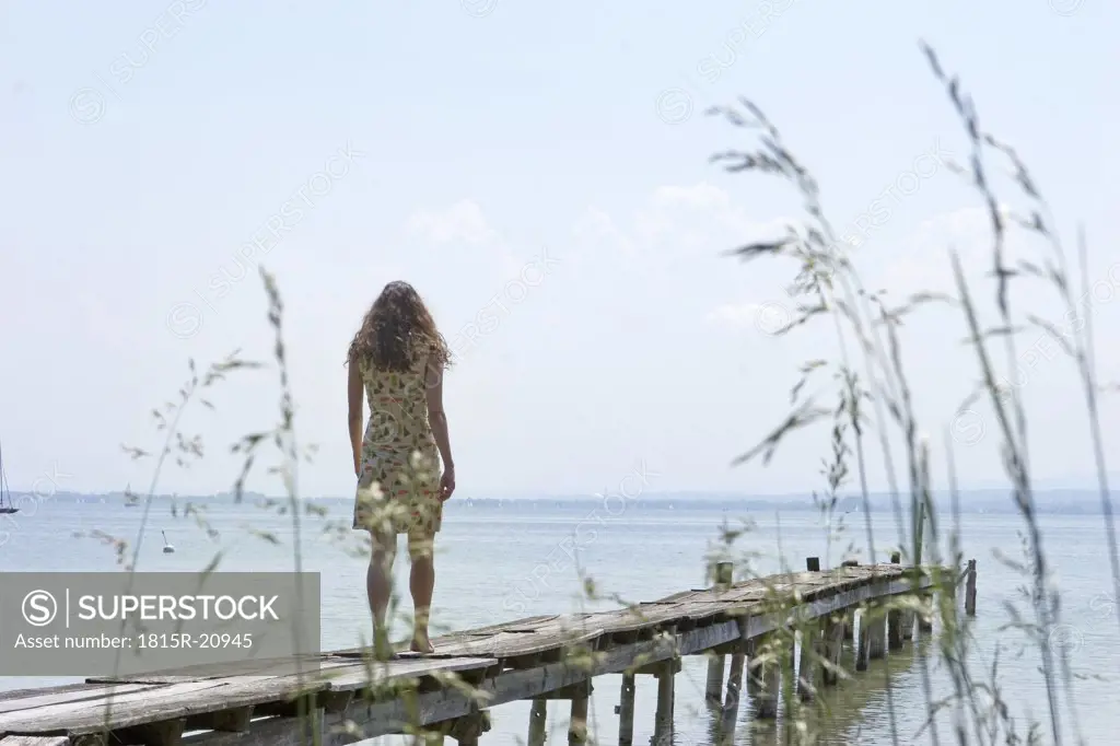 Young woman walking on jetty, rear view