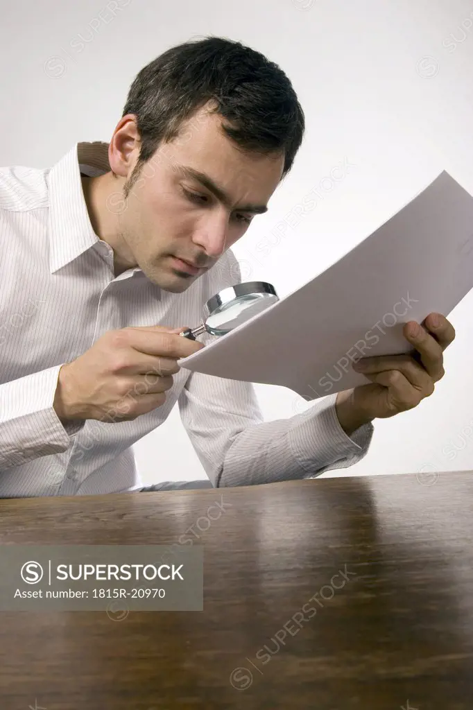 Man reading document with magnifying glass