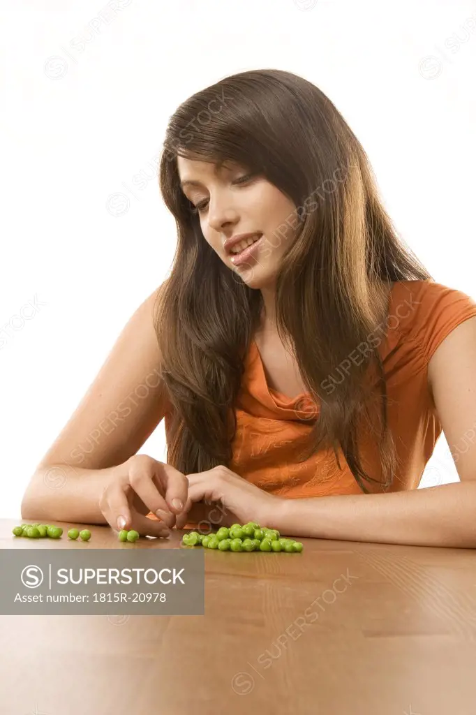 Young woman counting green peas, close-up