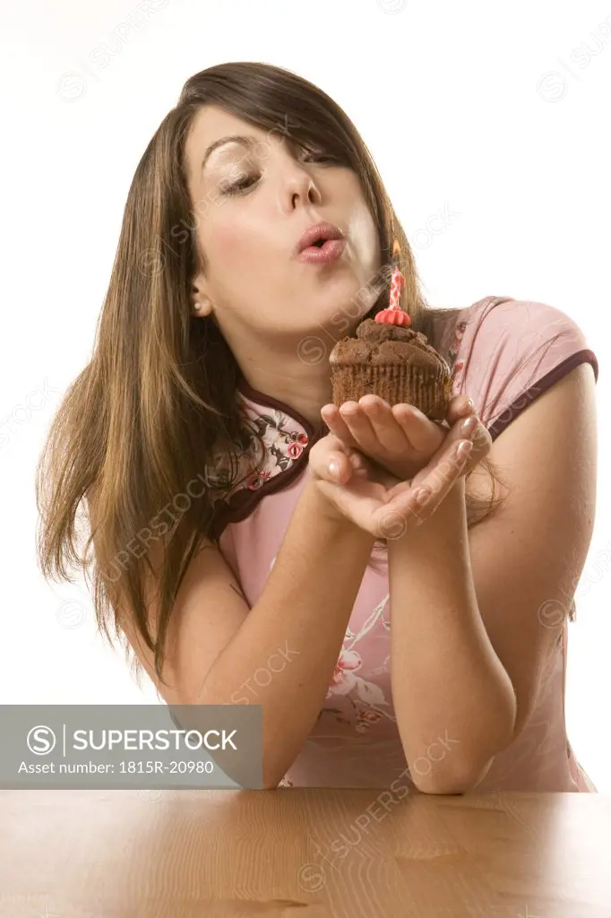 Young woman blowing candle on torte, portrait