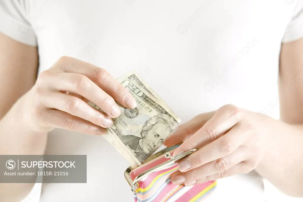 Woman putting Dollar notes in change purse, close-up