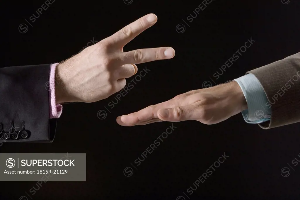 Businessmen playing rock paper scissors, close-up of hands